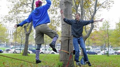Laura Lantz and Andrew Dekkinga of Slackline Pittsburgh high-five each other as they walk on the slackline ropes.