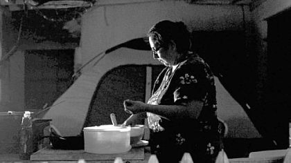 Beatrice Cortinas washes the dinner dishes by lamplight. For many weeks, the Cortinas family camped in their backyard after a bank foreclosed on their home and changed the locks.