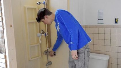 Christov Churchward, a student Conservation Association Fellow working with ACTION-Housing demonstrates different water conservation shower heads in the bathroom of ACTION-Housing's Pittsburgh Green House (PGH) in East Liberty. The house will be used as a training site for homeowners and contractors to learn how to make their homes more energy efficient.