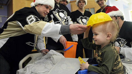 Penguins player Sidney Crosby places a toy hard hat on Camden Lookabaugh, 3, of New Kensington during a visit to Children's Hopsital of Pittsburgh of UPMC in Lawrenceville. Camden received a toy tool box from the players.