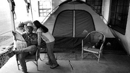 Armando Cortinas and his wife, Beatrice, spent much of the past few months living in their backyard, after a bank foreclosed on their home and changed their locks. They are fighting the eviction in court. Here, Armando reads a newspaper article to his granddaughter Angie, 8.