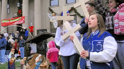 Morgan Prokovich, right, 17, holds a wooden cross at a community demonstration Friday in favor of Ellwood City?s creche displayed on the lawn of the municipal building.
