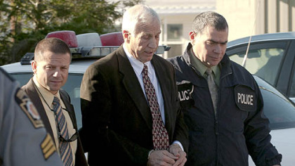 Former Penn State football defensive coordinator Gerald "Jerry" Sandusky, center, walks to the office of Centre County Magisterial District Judge Leslie A. Dutchcot on Nov. 5 in State College escorted by Pennsylvania State Police and Attorney General's Office officials.