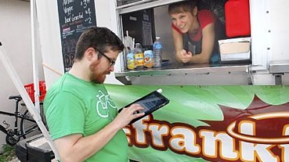 Dave White completes his order with one of Franktuary's owners, Megan Lindsay, at the Franktuary truck parked behind 2700 Jane St. on the South Side.