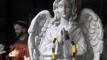 A black-and-gold rosary hangs on one of the angel figurines  in the showcase at the Sacred Heart of Jesus Catholic Store in Bloomfield.