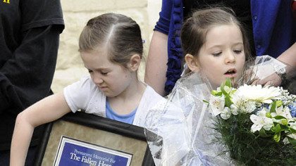 The daughters of slain officer Stephen Mayhle -- Jennifer, 8, left, and Brooklynn, 5, clutch a plaque and flowers presented to the families of Mayhle, Eric Kelly and Paul Sciullo II following the dedication of a sculpture of St. Michael.