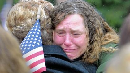 Retired Sgt. Jennifer Synuria, from New Stanton, holds a flag as she hugs Beverly Clark, the mother of fellow soldier Spc. Beverly S. Clark, who was killed when an Iraqi Scud missile destroyed the barracks of the 14th Quartermaster Detachment during Operation Desert Storm in 1991. Sgt. Synuria was injured in the attack. The two were at a ceremony marking the 20th anniversary of the attack at the Army Reserve Center in Greensburg.