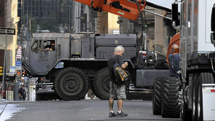 The crew of "The Dark Knight Rises" positions a scrim to block sunlight near Fourth Avenue for a scene in which an explosion drops a Tumbler vehicle into a blast crater constructed along Cherry Way.