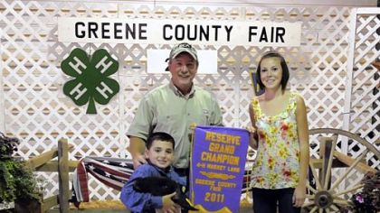 Rod Winters, left, of Energy Corporation of America, with his daughter, Parker, pose at the Greene County Fair after Mr. Winters bought the reserve Grand Champion lamb, seen with owner Hayden Demniak, 10, of Cumberland Township. Other energy companies also made purchases at the fair's 4-H Market Sale.