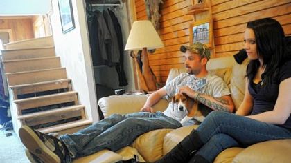 Bobby Guffey, 22, watches television with his girlfriend Maggie Gilbert, 19, and his dog Shooter at his home in Elizabeth Township.