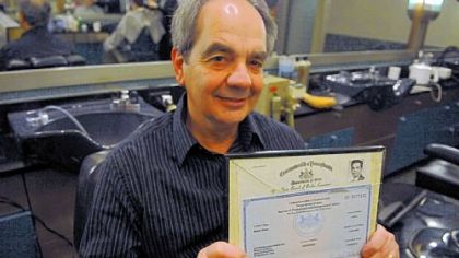 Ron Demutis, barber for more than 40 years at the barber shop in the Koppers Building, displays his license.