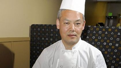 Dasonii Korean Bistro owner Bryan Chae with his mung bean pancake surrounded by a variety of side dishes, clockwise from top: tofu, green onions, cucumber, wild sesame leaf, kimchi and bean sprouts.