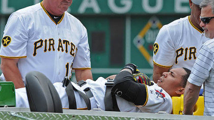 Pirates manager Clint Hurdle helps injured player Jose Tabata onto a stretcher.