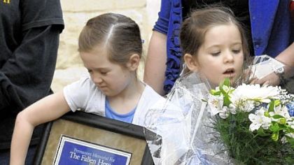 Jennifer, 8. and Brooklynn Mayhle, 5, clutch a plaque and flowers presented to their family in remembrance of their father, Officer Stephen J. Mayhle, who was killed on duty April 4, 2009. Plaques were also presented to the families of Officers Eric G. Kelly and Paul J. Sciullo II following the dedication of a sculpture of St. Michael as a memorial to the slain officers.
