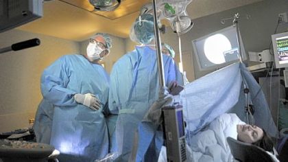 Dr. Stephen Emery, fetal surgeon, left, prepares to have the laser activated by the operating room team for surgery done to the placenta of Rachel Lendyak-Peters, right, which is being shared by her identical twins.