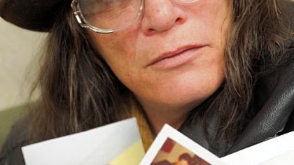 Rita Rave holds family photos of her longtime companion, Gary W. Miller, and their two children.