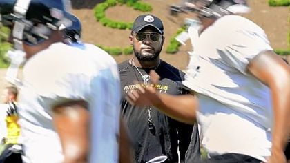 Coach Mike Tomlin keeps a close eye on players at warm-ups before Sunday workouts at training camp at Saint Vincent College.