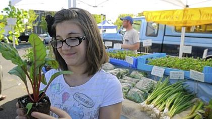 Zoe Moran, 11, of Arlington holds up a red swiss chard plant she selected from the "Who Cooks for You Farm," from New Bethlehem, Pa., on opening day of the CitiParks Farmers Market in East Liberty. Zoe was part of a group of Pittsburgh Montessori School fourth- and fifth-graders who went to the market to buy locally grown food to make a harvest meal.