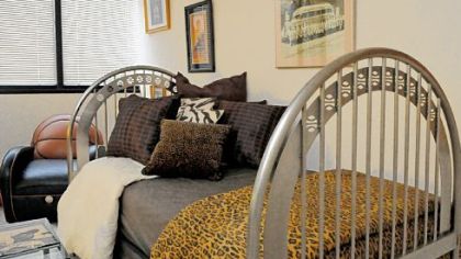 Bed with a basketball theme in a bedroom with sports memorabilia in Robert Hill's Trimont condo.
