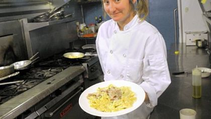 Chef Kate Romane holds a dish of farfalle with prosciutto cream and peas in the kitchen of E&sup2; in Highland Park.