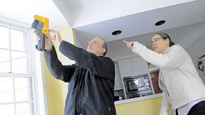 Constantine Paliouras of Pro Energy Consultants shows Kerry McGee how he uses instruments to detect air leakage in her Mt. Lebanon home.