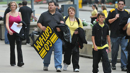 Jeff Aldrich of Wilkins carries a "Go  Gotham" sign as he and his wife Donna  head into Heinz Field today to take part in the filming of a football sequence for "The Dark Knight Rises", the new Batman film.