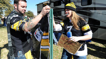 Steelers fans Chris Kirkpatrick of Orlando, Fla., formerly of Clarion, and Katy Dierks of Los Angeles, hang a Steelers flag outside the RV they drove with friends from Orlando to Texas to see the game.
`
