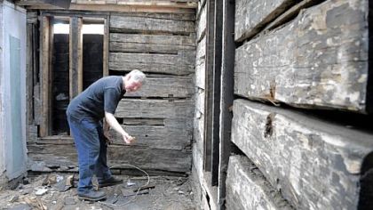 Lawrenceville architect Keith Cochran pulls a peg from one of the large logs in the home at Charlotte and 38th streets in Lawrenceville, below. The 1822 log home may be torn down, but the logs could be saved and cataloged until they can be reassembled somewhere else in Lawrenceville.