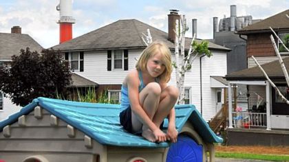 Danika Evans, 8, plays in her front yard with GenOn Energy's Elrama power plant in the background. The plant is considered a major source of pollution in the area. An electric power research group acknowledges that there are health effects from air pollution.