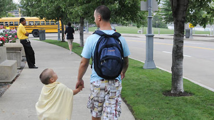 Jeremy Prata of Shaler walks with his son Ben, wearing a batman cape, near Heinz Field after watching some of the moviemaking action today.