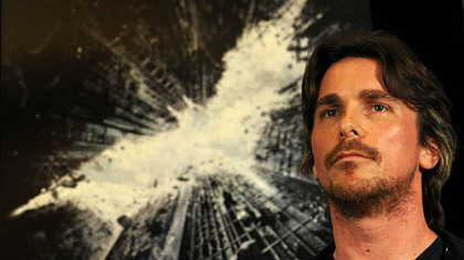 Actor Christian Bale listens to director Christopher Nolan and others at a press conference for "The Dark Knight Rises" at the Renaissance Hotel, Downtown.