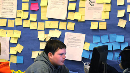 Jordan Helterbran, a ninth-grader at Pittsburgh Langley High School, works on his resume in a room filled with "stickies" of comments by students about others' essays.