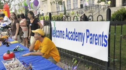 Muzz Meyers from Communities in Schools sits at the welcome table to talk with parents outside the Academy at Westinghouse.
