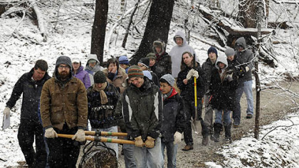 Carrying a roll of jute netting, participants in the Pittsburgh Parks Conservancy workshop in Urban EcoSteward Erosion Control Training make their way through snow-covered Riverview Park on Pittsburgh's North Side Sunday morning.