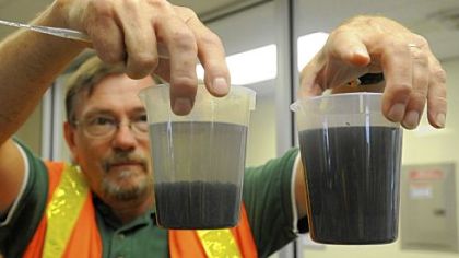 Kevin Warheit, a product manager with Siemens, holds two samples of flowback water. The water on the left has been treated with a polymer and coagulant to make the particles form a sludge. The sludge is then put into a filter press and made into a nontoxic cake that can be disposed of.