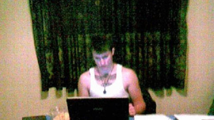 Richard Poplawski, dressed in a white tank top, sits at a table at his laptop. Spread before him are a number of weapons, including an assault rifle, handgun, a long gun, gun belt, banana clips and ammunition. This was presented as evidence Thursday during Mr. Poplawski's trial.