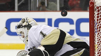 A puck goes flying behind Penguins goaltender Brent Johnson during the second period of Thursday's game against the Devils in Newark, N.J.