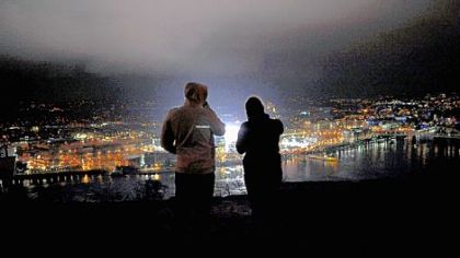 A man and a woman look out over a lit Heinz Field hours before the start of the Winter Classic from Mt. Washington last night.