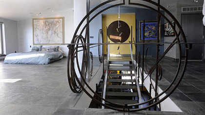 Second-level open floor plan with master bedroom, shower and office space. The 26-by-30-foot area has a queen bed on the floor with banks of floor-to-ceiling windows. A flat-screen TV hangs on the wall and can be pulled out for nighttime viewing. Glass doors open to a second terrace. The floating staircase was created by Peter Michael Lambert of Red Star Ironworks.