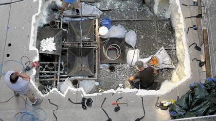 Pedestrians watch as film workers rig the bottom of a hole dug on Tuesday in Cherry Way between Forbes and Fourth avenues, Downtown. The hole will be used this week in a stunt for the Batman movie.