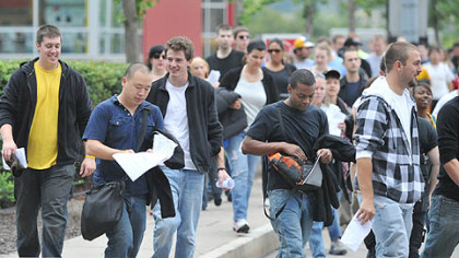 Extras, including (center left) Wei Yu of Boston and Schevon Salmon of Florida, head into Heinz Field as "The Dark Knight Rises" films at the stadium. They  are both law students at the University of Pittsburgh.