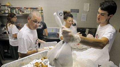 A group of Lasallian volunteers pack take-home food as they help prepare and serve the Sunday mid-day meal at the Jubilee Kitchen on Wyandotte Street in the Hill District. The volunteers are on a cross-county bike trip to promote service and fight poverty.