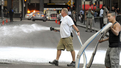 Fake snow is sprayed on Oliver Avenue at William Penn Place before filming begins Wednesday in Downtown Pittsburgh.
