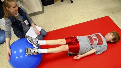 Evan Lau works out with Kristin Fortner, an occupational therapist, to improve his strength to battle Reflex Neurovascular Dystrophy at the Children's Institute in Squirrel Hill.