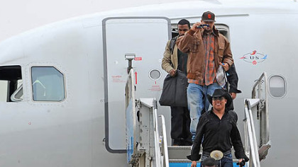 Hines Ward wears a cowboy hat and large belt buckle as he makes his way off the jet.