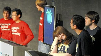 All University of Pittsburgh team members, from left, Danielle Arbogast, Richard Kester, Brian Sisco and CMU team members, from far left, Connor Fallon, Will Zhang and Erik Schmidt can do is to wait for their turns while IBM Watson, center, "answers" the questions during a Jeopardy exhibition game at CMU on Wednesday.This is the first time students will have the chance to face Watson's analytical capabilities.