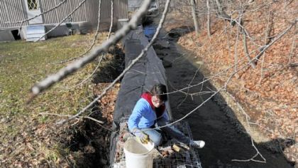 Junior Janie Owens, 23, of Tulare, Calif., adds rocks to a wall Monday as a group of Geneva College students use their spring break vacations to work on flood control at a trailer park off of Spring Street in Aliquippa.
