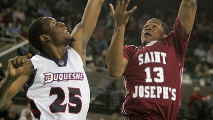 Saint Joseph's Ronald Roberts takes a shot as Duquesne's Damian Saunders defends in the second half of yesterday's Atlantic 10 tournament game in Atlantic City, N.J.