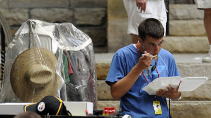A crew member eats lunch next to a wardrobe rack outside Trinity Cathedral, Downtown, during filming on Aug. 10.