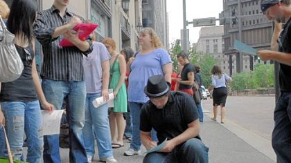 Some of the many people hoping to be extras in the next Batman movie, being filmed in part in Pittsburgh, fill out forms while waiting in the blocks-long line Downtown. Some waited as long as four hours for a shot at a spot in the film.